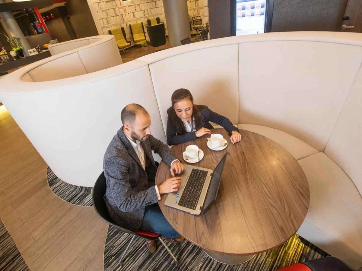 two men sitting at a table with a laptop at ibis London Blackfriars in London