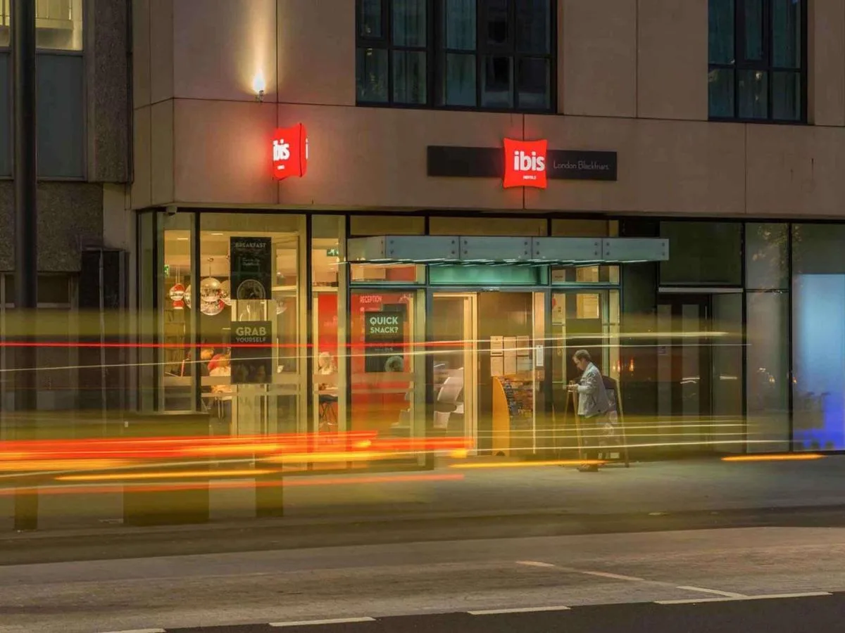 a man walking in front of a building at night at ibis London Blackfriars in London