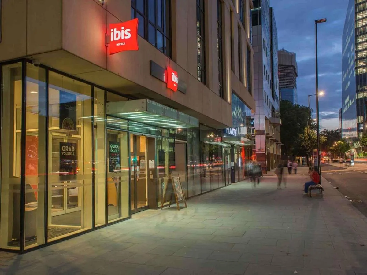 a city street with people walking in front of a store at ibis London Blackfriars in London