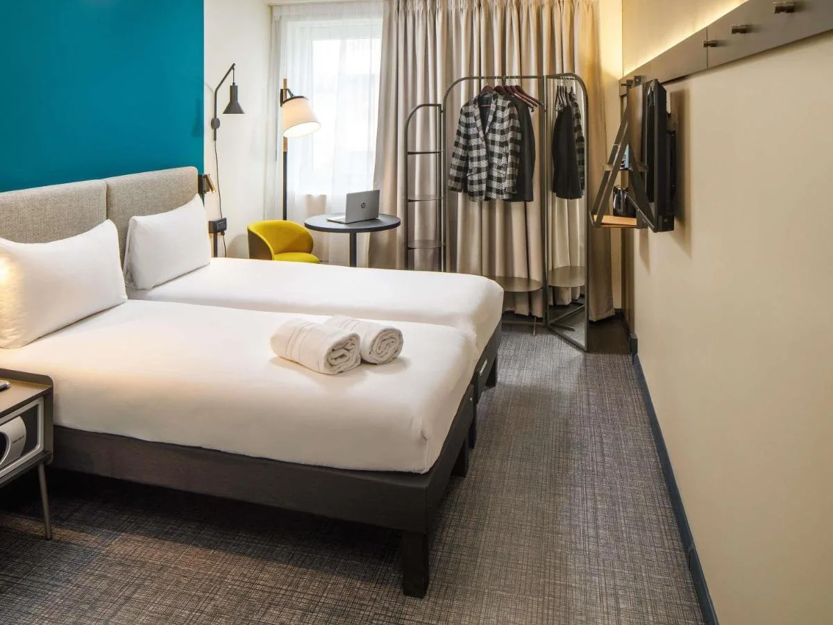 a hotel room with two beds and a chair at ibis London Blackfriars in London